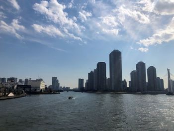 Sea by buildings in city against sky