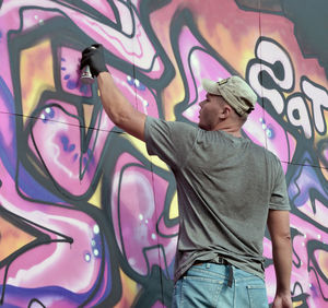 Rear view of man standing against graffiti wall