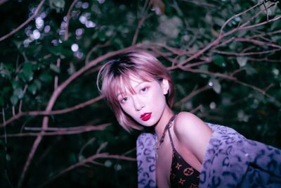 Portrait of a young woman against plants