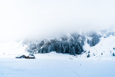 Beautiful villa situated in the snowy mountain alps surrounded by fog.