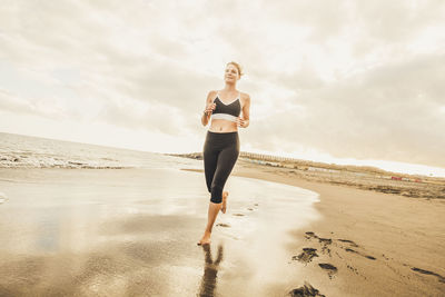 Low angle view of woman running on beach