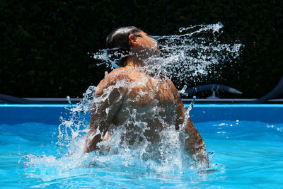 Man splashing water in swimming pool