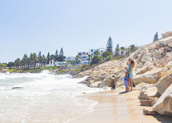 People walking on beach against clear sky