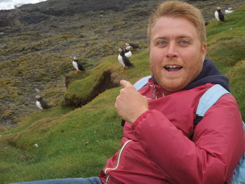 Portrait of smiling young man with birds on grass