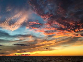 Scenic view of sea against dramatic sky during sunset