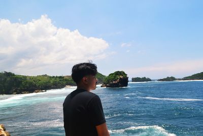 Boy standing in sea against sky