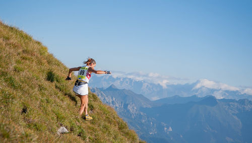 Rear view of man standing on mountain against clear sky