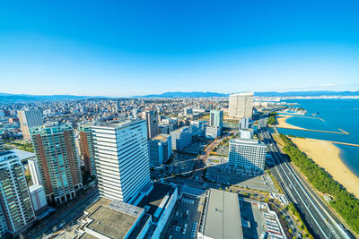 High angle view of city buildings against blue sky