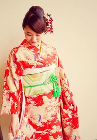 Young woman wearing kimono against beige wall