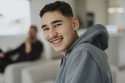 Portrait of smiling teenage boy sitting in living room at home