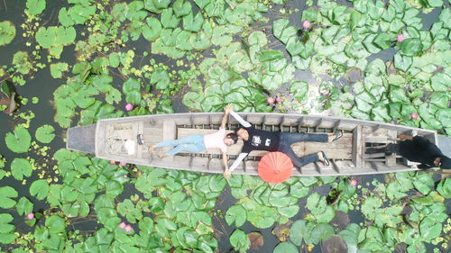 High angle view of couple lying in boat on lake