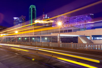 Light trails on road against buildings at night