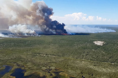 Smoke emitting from volcanic landscape against sky