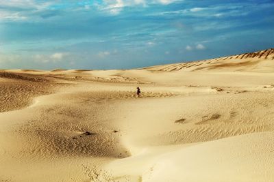 Mid distant view of man standing in dessert against sky