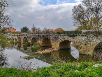 Arch bridge over river against sky