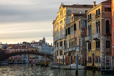 Canal amidst buildings against sky during sunset