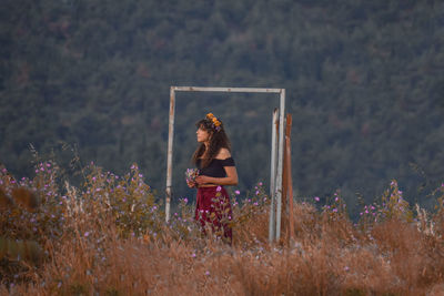 Woman standing on field by flowering plants