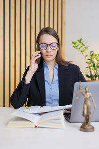 Young woman using mobile phone while sitting on table