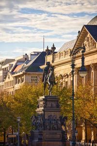 Statue in city against sky