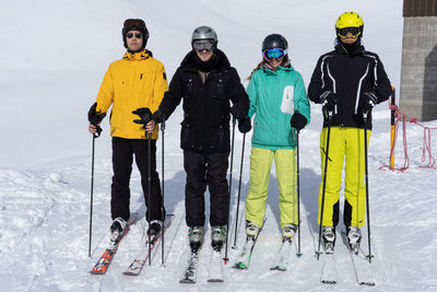 Friends standing on snow covered mountain during skiing