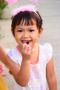 Portrait of cute girl eating berry while standing outdoors