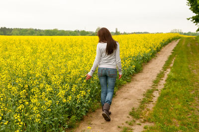 Rear view of young woman walking on field