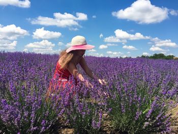 Woman amidst lavender flowers on field against sky