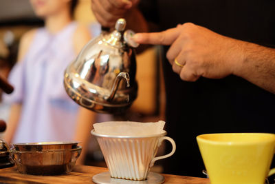 Midsection of man preparing coffee on table