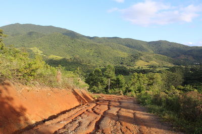 Scenic view of road by mountains against sky