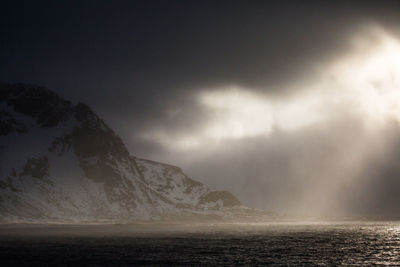 Scenic view of sea by mountain against sky