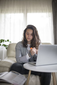 Young woman using phone while sitting on sofa