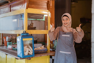 Portrait of smiling woman standing at street food stall