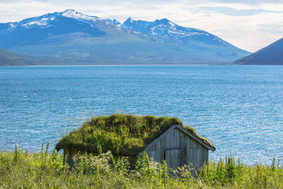 Hut by lake with mountains in background