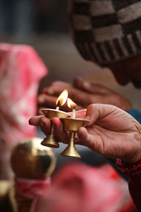 Close-up of hand holding burning diyas