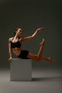 Full length of woman exercising against black background