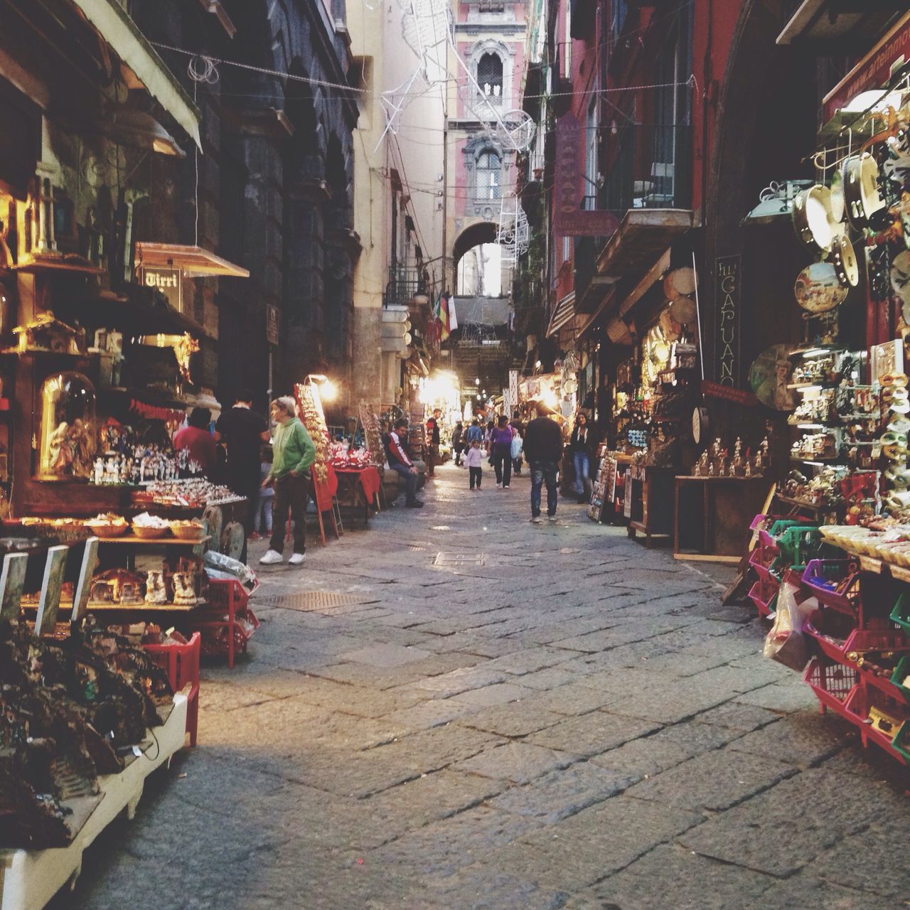 architecture, building exterior, built structure, the way forward, street, city, market, illuminated, diminishing perspective, cobblestone, incidental people, market stall, retail, alley, narrow, store, residential building, multi colored, city life, outdoors