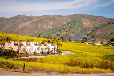 Scenic view of field and houses against sky