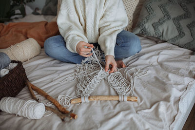 Young girl weaves using macrame technique at home