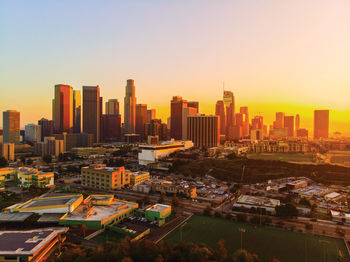 Aerial view of city buildings against clear sky during sunset