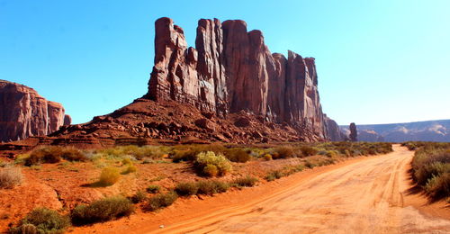 Road amidst rocky mountains against clear sky