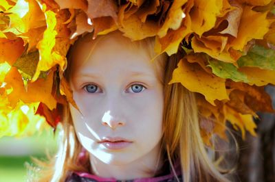 Close-up of a girl in autumn in a hat made of leaves