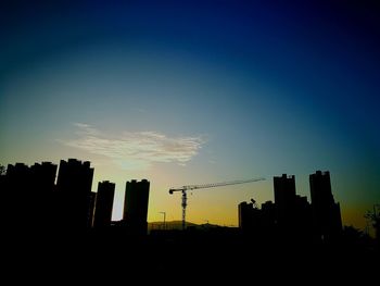 Low angle view of silhouette skyscraper against sky during sunset