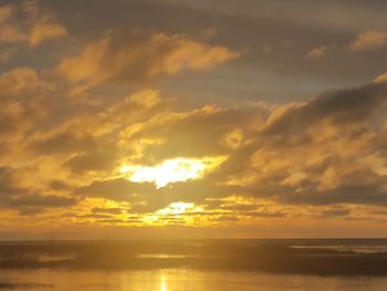 Scenic view of sea against dramatic sky during sunset