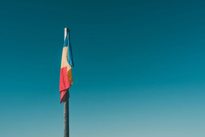 Low angle view of flag against clear blue sky