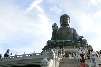 Low angle view of buddha statue against cloudy sky