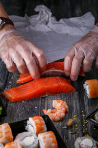 Midsection of man slicing fishes at table