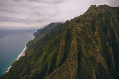 Scenic view of sea by mountain against sky