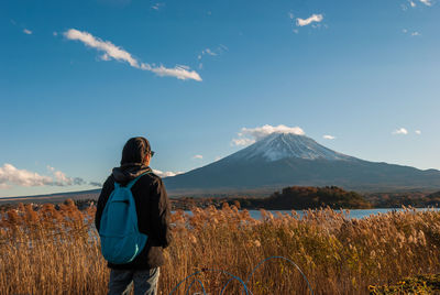 Rear view of man standing on land against sky