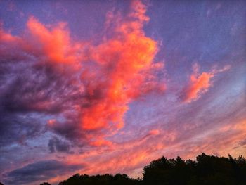 Low angle view of silhouette trees against dramatic sky