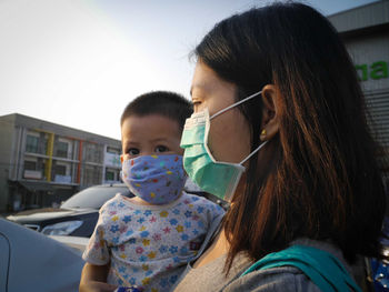 Close-up of mother wearing mask carrying son